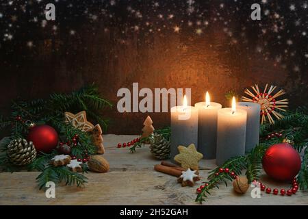 Troisième Avent, trois des quatre bougies sont illuminées, boules rouges, branches et biscuits de pain d'épice comme décoration de Noël sur des planches rustiques en bois, b foncé Banque D'Images