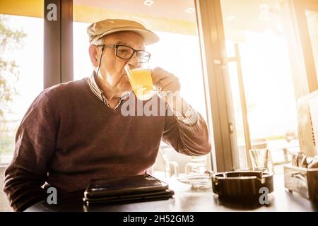 L'homme âgé est assis dans un café et boit du thé. Banque D'Images