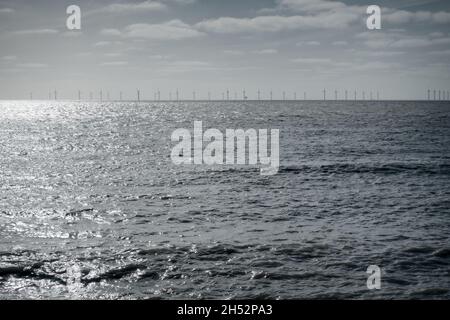 Éoliennes offshore à l'horizon à Clacton-on-Sea, Essex, avec la mer grise en premier plan et le ciel gris-bleu en arrière-plan. Banque D'Images