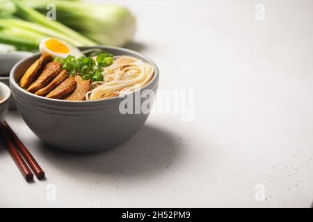 Ramen avec de la viande et des légumes, les ingrédients de la table avec des garnitures telles que le porc en tranches, l'oeuf.Fond en béton gris Banque D'Images