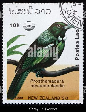 LAOS - VERS 1990: Un timbre imprimé au Laos montre tui, prostemadera novaeseelandie, est un oiseau de passereau endémique de la Nouvelle-Zélande, vers 1990 Banque D'Images