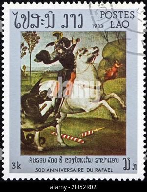 LAOS - VERS 1983 : un timbre imprimé au Laos montre Saint-Georges et le dragon, du Louvre, Paris, peinture de Raphaël, vers 1983 Banque D'Images