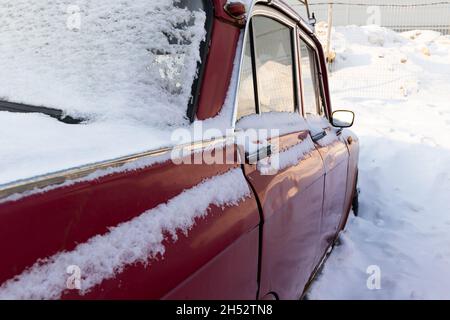 vieille voiture rétro brisée rouge rouillé vieux garé en hiver sur fond de neige le jour d'hiver glacial Banque D'Images