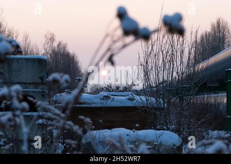 tuyaux de chauffage central dans une gaine d'isolation thermique métallique de protection posé au-dessus du sol lors d'une soirée d'hiver froide à coucher de soleil Banque D'Images