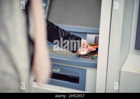 Gros plan d'une femme utilisant un distributeur de billets dans la rue.Marche, guichet automatique, ville Banque D'Images