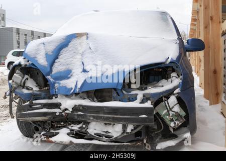 la voiture bleue s'est écrasée sans phares ni pare-chocs après un accident garé par la route sous une couche de neige une journée d'hiver froide Banque D'Images