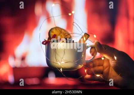 Une jeune femme tient un mug de noël sur une cheminée, gros plan, spiritueux de noël, photographie en intérieur Banque D'Images