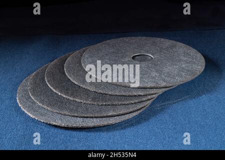 Un disque à tronçonner pour une meuleuse sur une table bleue.Outils de serrurier sur fond noir Banque D'Images