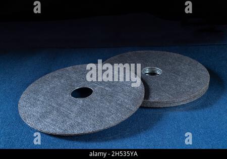 Un disque à tronçonner pour une meuleuse sur une table bleue.Outils de serrurier sur fond noir Banque D'Images