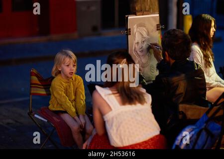 Paris, France - juillet 2019 : peintre de Montmartre présentant un enfant à la place du Tertre la nuit, à quelques rues de la basilique de Montmartre Banque D'Images