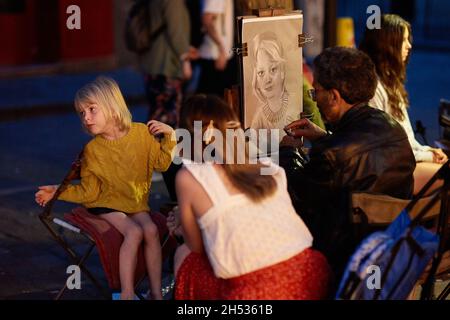 Paris, France - juillet 2019 : peintre de Montmartre présentant un enfant à la place du Tertre la nuit, à quelques rues de la basilique de Montmartre Banque D'Images