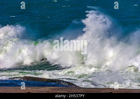 De fortes vagues s'écrasant contre les rochers lors d'une tempête par temps ensoleillé Banque D'Images