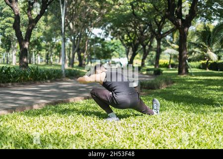 Tenue sportive active jeune homme en noir sportswear faire des exercices de sport dans le parc.Vue arrière.Concept de mode de vie sain, sport extérieur Banque D'Images