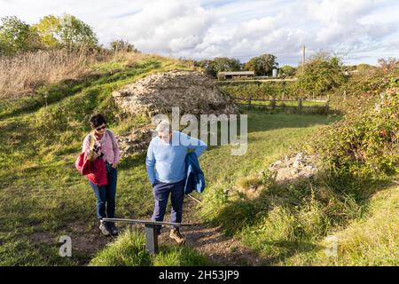 Un homme et une femme touriste lisant un panneau d'information à la porte nord de la muraille de ville romaine en ruines à Silchester, Hampshire, Royaume-Uni Banque D'Images