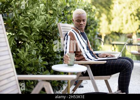 Latin homme utilisant un ordinateur portable sur la chaise longue dans le jardin de la maison Banque D'Images