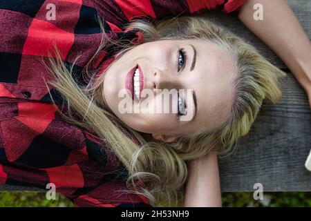 belle jeune femme blonde allongée sur un banc, vue d'en haut, juste au-dessus d'elle, tout en relaxant - concept de bonheur Banque D'Images