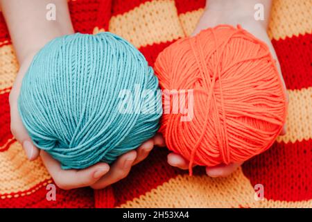 deux pelées de couleur en laine dans les mains sur une nappe tricotée jaune-rouge.Photo de haute qualité Banque D'Images