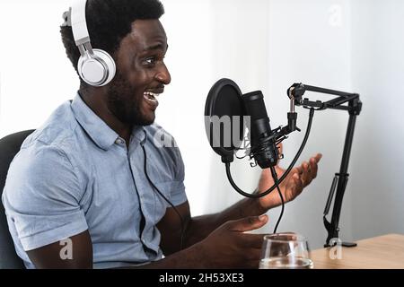 Homme africain enregistrant un podcast à l'aide d'un microphone et d'un casque de son studio Banque D'Images