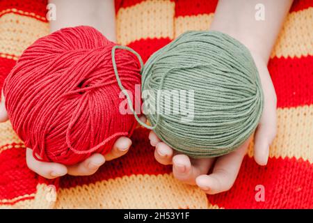 deux pelées de couleur en laine dans les mains sur une nappe tricotée jaune-rouge.Photo de haute qualité Banque D'Images