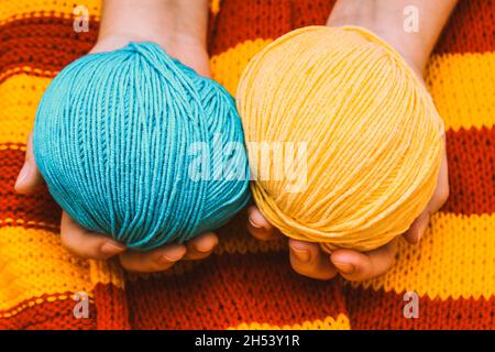 deux pelées de couleur en laine dans les mains sur une nappe tricotée jaune-rouge.Photo de haute qualité Banque D'Images