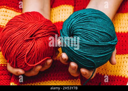 deux pelées de couleur en laine dans les mains sur une nappe tricotée jaune-rouge.Photo de haute qualité Banque D'Images