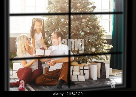 Grande famille avec trois enfants célébrant Noël à la maison.Dîner festif au foyer et arbre de Noël.Les parents et les enfants qui mangent au feu se trouvent dans Banque D'Images