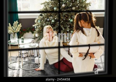 Grande famille avec trois enfants célébrant Noël à la maison.Dîner festif au foyer et arbre de Noël.Les parents et les enfants qui mangent au feu se trouvent dans Banque D'Images