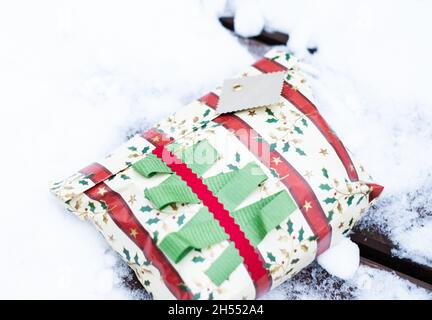 Cadeau de Noël dans la neige.Cadeau de Noël magnifiquement enveloppé, installé à l'extérieur dans un environnement naturel pendant l'hiver, les fêtes. Banque D'Images