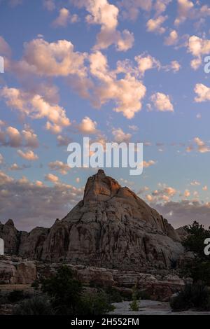 Des nuages blancs boursouflés surent les rochers dans le désert au lever du soleil dans le parc national de Capitol Reef Banque D'Images