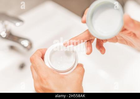 Mains de femme tenant un pot de crème hydratante. Banque D'Images