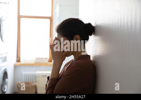 Jeune femme indienne debout dans la buanderie et pleurant Banque D'Images