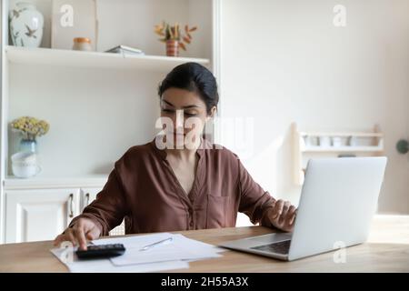 Focalisée femme indienne calcule les dépenses payer des factures et des impôts en ligne Banque D'Images