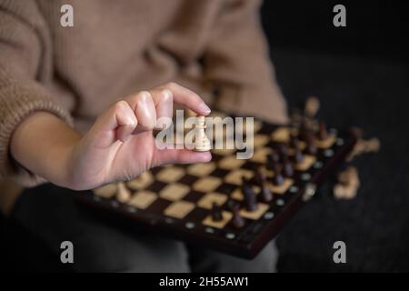 Gros plan d'une pièce d'échecs dans les mains des femmes, arrière-plan flou. Banque D'Images