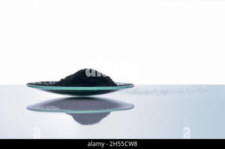 Poudre de charbon de carbone dans le verre de surveillance chimique.Gros plan sur l'ingrédient chimique sur la table de laboratoire blanche.Vue latérale Banque D'Images