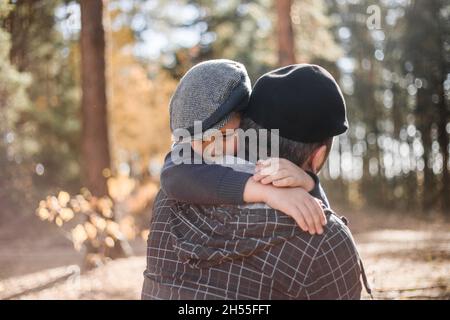 Fête du père.Triste fils embrassant papa sur le fond de la forêt avec l'espace de copie.Concept de relation père-fils Banque D'Images