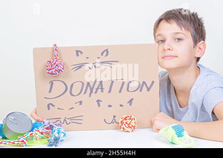 Enfant souriant tenant un morceau de carton brun avec inscription Don et dessins de chats et d'un chien.Bénévoles collectant un don pour un animal Banque D'Images