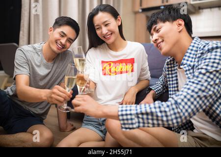 De jeunes hommes heureux buvant du champagne dans le salon Banque D'Images