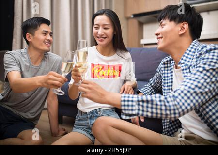 De jeunes hommes heureux buvant du champagne dans le salon Banque D'Images