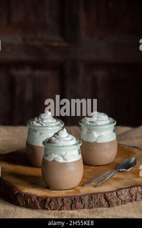 Une mousse au chocolat. Trois récipients en verre avec ce délicieux dessert. Table et toile de fond en bois vintage. Espace pour les copies. Banque D'Images