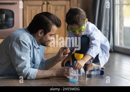 Le père millénaire et le fils préadolescents qui s'occupent de lui font des expériences chimiques amusantes Banque D'Images