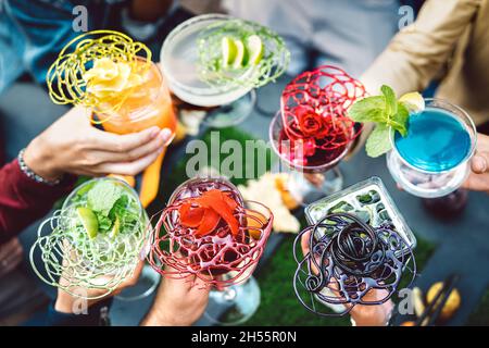 Les gens toaster les cocktails fantaisie multicolores - les amis qui s'amusent à boire des spécialités fraîches au bar de la mode happy hour - heure de la fête des boissons Banque D'Images