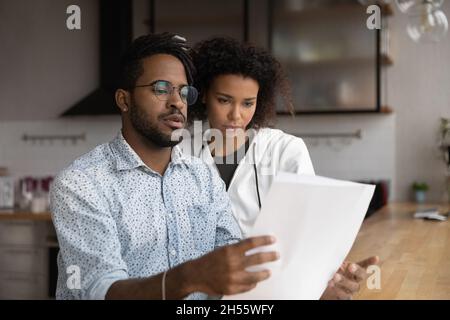 Focalisé souligné jeune couple divers lisant la lettre papier. Banque D'Images