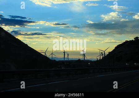 Paysage avec centrales éoliennes derrière les collines le soir | photo d'un parc éolien pris en voiture, vues depuis la fenêtre de la voiture pendant la conduite Banque D'Images