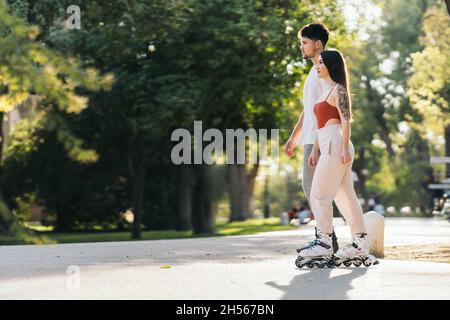 Rayons du soleil éclairant deux personnes qui patinent dans un parc Banque D'Images