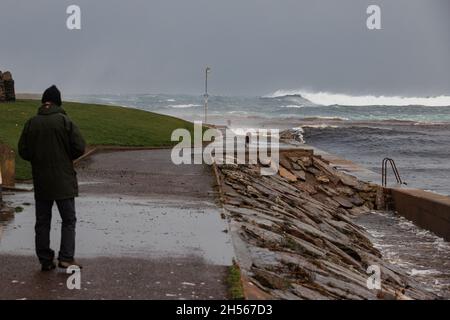 Thurso, Écosse.Novembre 7 2021.Un homme observe des vagues de tempête se brisant à Thurso East.Les vagues ont été générées par des vents de force géale dans la mer du Nord. Banque D'Images