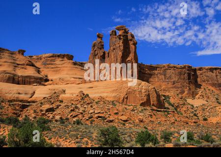 Le parc national Arches est populaire avec trois Sœurs, vue arrière sous un ciel bleu avec des nuages incroyables formations rocheuses forme d'êtres humains sur un piédestal en pierre Banque D'Images