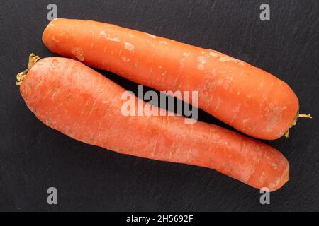 Deux carottes rouges bio non pelées sur un plateau en ardoise, vue rapprochée du dessus. Banque D'Images