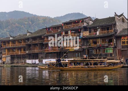 Hunan, Chine, 14 Novembre 2011 : l'homme l'aviron bateau en bois le long de la rivière de l'ancienne rue. Banque D'Images