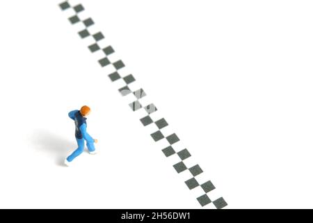 Photographie miniature de personnage de jouet de personnes.Un jeune homme qui court vers la ligne d'arrivée, isolé sur fond blanc.Photo d'image Banque D'Images