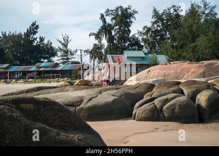 Moto se trouve sur une grande pierre sur la plage.Plage en Asie avec de grands rochers et des maisons colorées.Photo de haute qualité Banque D'Images